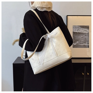 Detail of cream tote bag featuring embossed puppy patterns and a delicate lace bow accent
