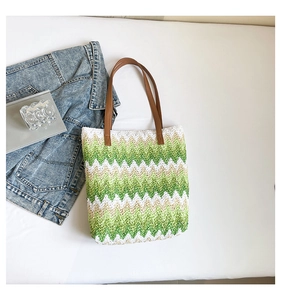 Macro detail of zigzag woven pattern on a spacious straw tote bag with brown handles