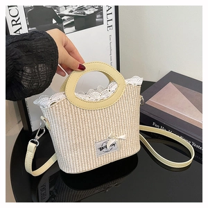 Détail du sac seau en paille avec bordure en dentelle, poignées crème et nœud décoratif