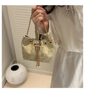 Detail of straw bucket bag with floral embroidery, gold chain handle and pearl drawstring