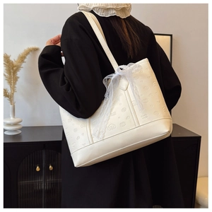 Detail of cream tote bag featuring embossed cartoon patterns and a white lace bow decoration