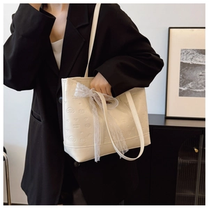 Detailed close-up of cream white tote bag with embossed textures and delicate lace ribbon decoration