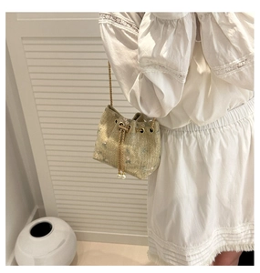 Detail of straw bucket bag with floral embroidery, drawstring and pearl accents