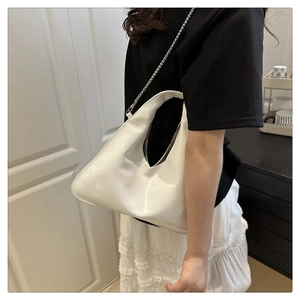 Close-up of white glossy crossbody bag with silver chain strap and polished finish