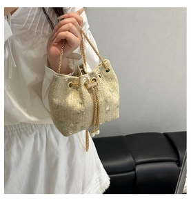 Detail of straw bucket bag featuring pink flower embroidery and pearl drawstring tassels