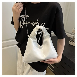 Close-up of white patent leather shoulder bag with chic cutout handle and silver chain strap