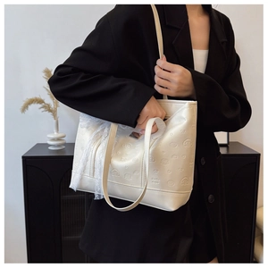 Detail view of cream tote bag with cartoon embossment and lace bow accessory