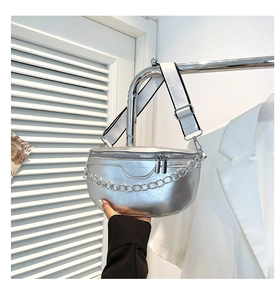 Detail van de zilveren zadeltas met grove metalen ketting en brede geweven riem