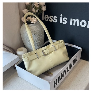 Detail of light yellow retro baguette bag with glossy leather and buckle strap