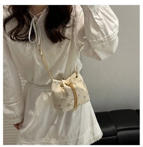 Detailed close-up of floral embroidery and pearl drawstring on a straw bucket bag