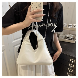 Close-up of white glossy patent leather tote bag with modern integrated handle design