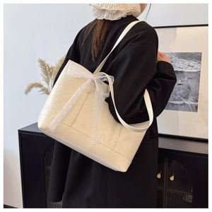 Detail view of cream white tote bag with embossed pattern and delicate lace bow accent