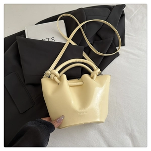 Detail of light yellow bucket bag with pleated drawstring top and PU leather texture