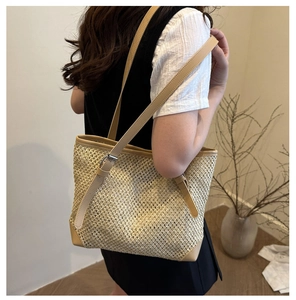 Detail of adjustable brown leather straps and hollow woven texture on the beige tote bag