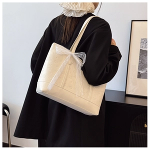 Close-up of cream tote bag with lace bow and cute embossed pattern on matte leather