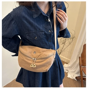 Khaki nylon crescent shoulder bag with metal detail and white zipper tabs on model