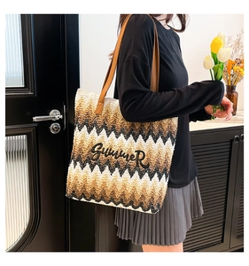 Close-up of chevron woven straw tote with Summer embroidery and brown leather straps