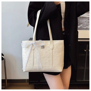 Detail of cream tote bag with Smile Doggie embossed pattern and white lace bow accessory