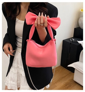 Gros plan détaillé d'un sac à main rose avec une grande anse nœud et une bandoulière chaîne