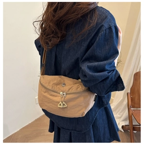 Detail of khaki nylon crossbody bag showing crinkled texture and triangular zipper pull
