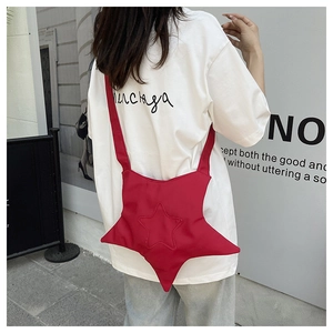 Street style shot of red star-shaped canvas crossbody bag with detailed stitching
