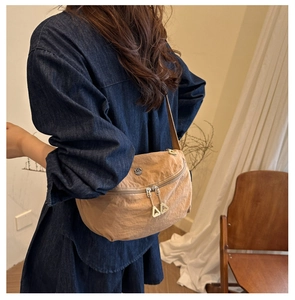 Rear view of model wearing a khaki nylon crossbody bag with triangular zipper detail