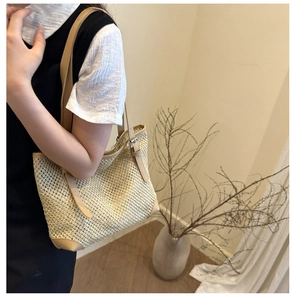 Detail of woven straw tote bag featuring tan leather straps and silver buckle adjustment