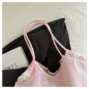 Close-up of pink translucent camisole with delicate white floral embroidery details
