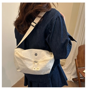 Detail of beige nylon crossbody bag with pleated texture and triangular zipper pull