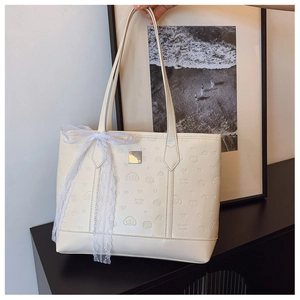 Detail shot of cream white tote bag featuring embossed puppy patterns and lace bow decor