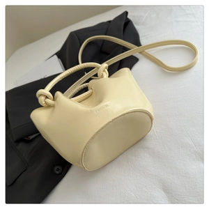 Detail of cream white pleated bucket bag with knot handle and Lucky Bag Fashion logo
