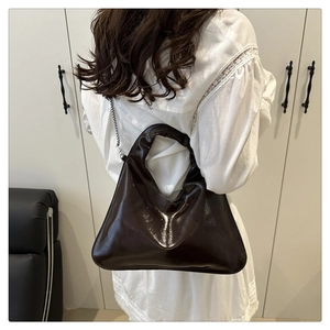 Detailed view of glossy dark brown Hobo bag with metallic chain strap worn by a model