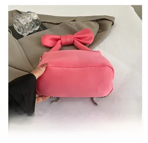 Vue détaillée de la base large d'un sac à main rose avec nœud et chaîne métallique