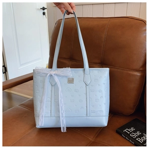 Close-up of light blue tote bag with embossed cartoon patterns and white lace bow detail