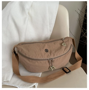 Detail of light brown waterproof nylon crescent bag featuring unique green zipper pulls