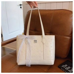 Detail of cream tote bag featuring embossed cartoon patterns and a white lace bow accent