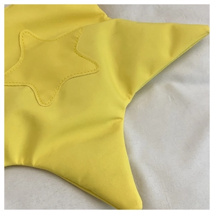 Détail de sac en toile jaune en forme d'étoile avec coutures décoratives et texture fine du tissu