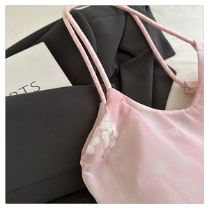 Close-up of pink silk camisole featuring delicate white floral embroidery and double straps