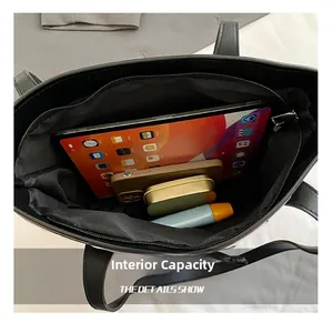 Macro shot showing internal capacity of black leather tote bag with tech and daily items