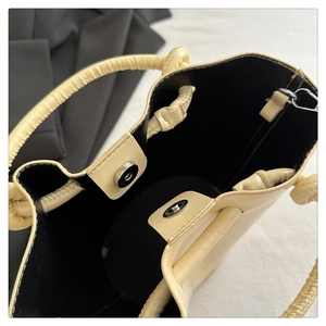 Detail view of cream bucket bag showing magnetic snap closure and black interior lining