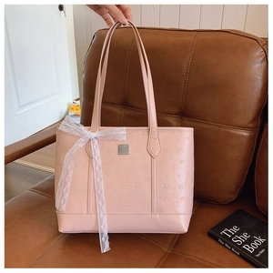 Detailed texture of pink leather tote bag featuring heart embossing and lace bow detail