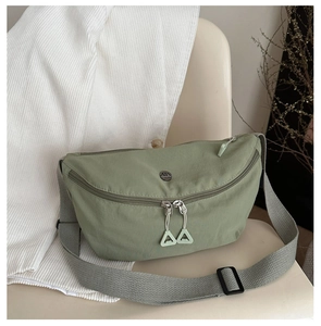 Detail view of fruit green nylon fabric and metallic circular logo on the crossbody bag