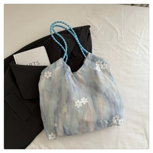 Detailed view of the daisy embroidery and blue-grey artistic dye pattern on large tote bag