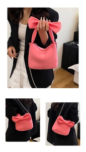 Détail d'un sac à main rose avec une grande anse en nœud et une bandoulière chaîne argentée