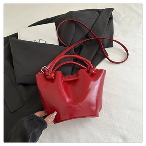 Close-up of red patent leather bucket bag with knotted handle and FUFD brand embossing