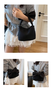 Détail du sac à main noir orné d'un grand nœud et d'une bandoulière en chaîne métallique