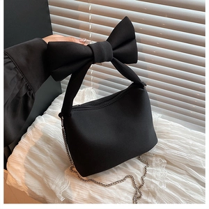 Detailed view of the large bow handle and silver metal zipper on a black canvas bag