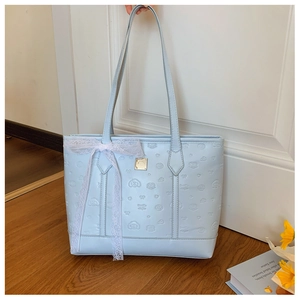 Detail of light blue tote bag featuring embossed cartoon patterns and a white lace bow