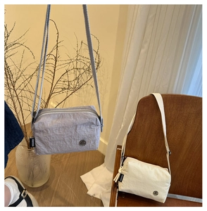 Detail of grey and beige wrinkled texture crossbody bags on a wooden chair