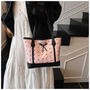 Detail of pink ruffled tote bag featuring black bow embroidery and slim leather handles